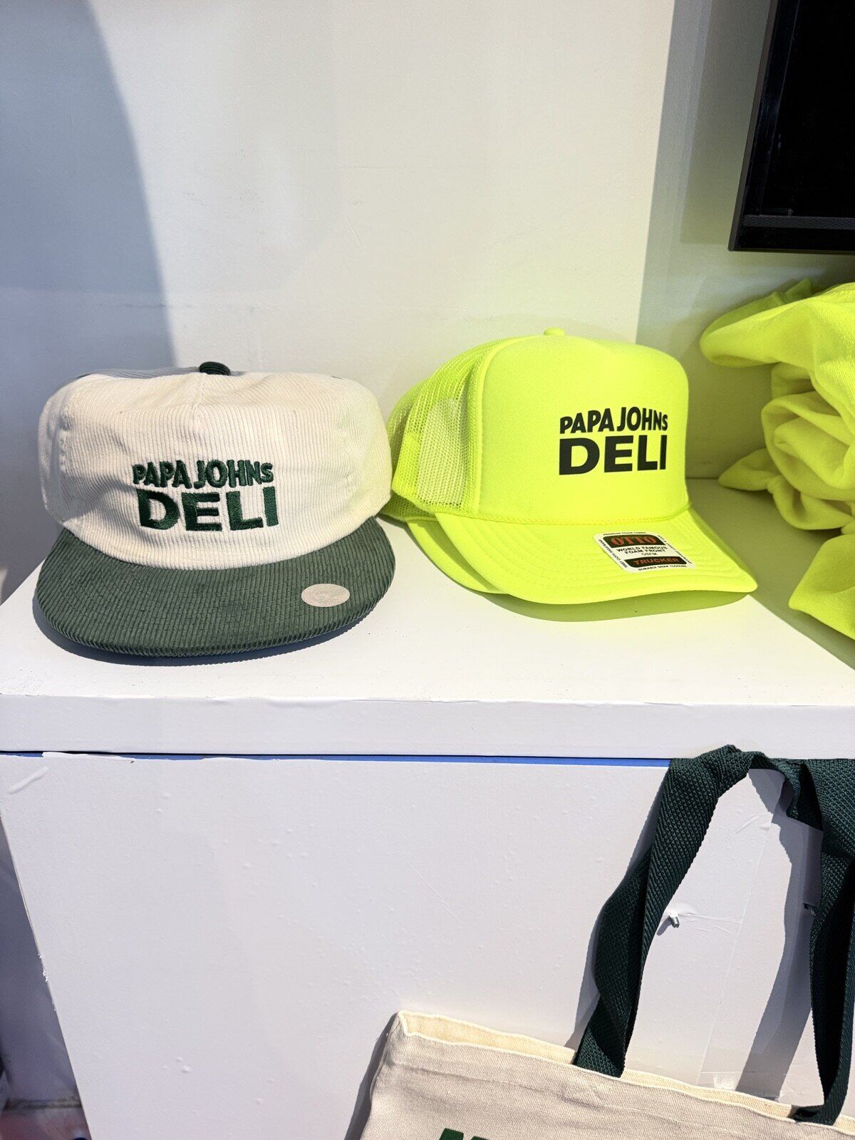 Branded event swag display wall with printed shirts and tote bags at a live Merch Troop station
