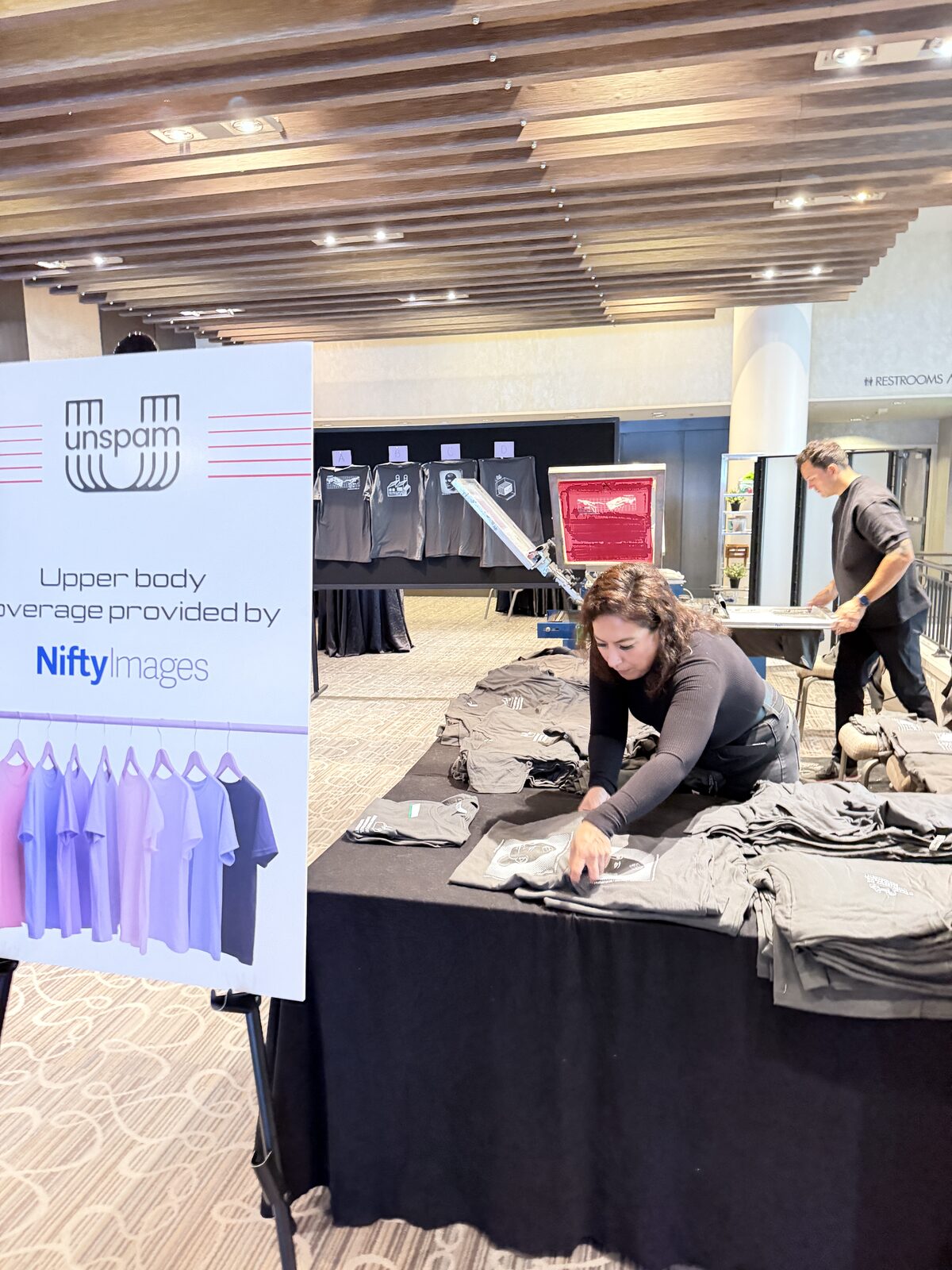 Conference welcome-kit table stocked with freshly printed event swag shirts