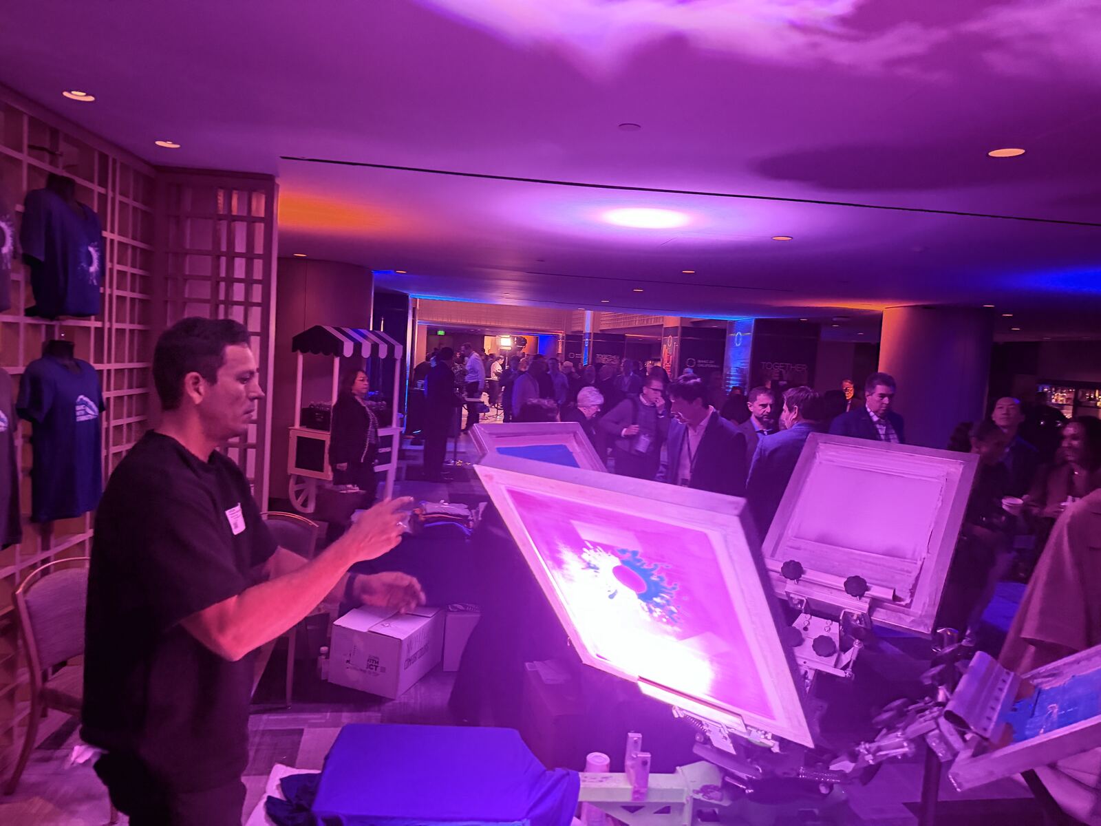 Staff at a live printing booth showcasing decorated apparel to guests